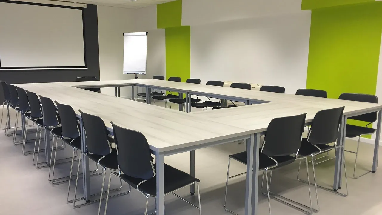 Salle de formation disposée en U, prête pour un atelier, paperboard au fond